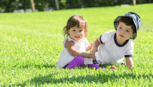 Two children playing on grass.